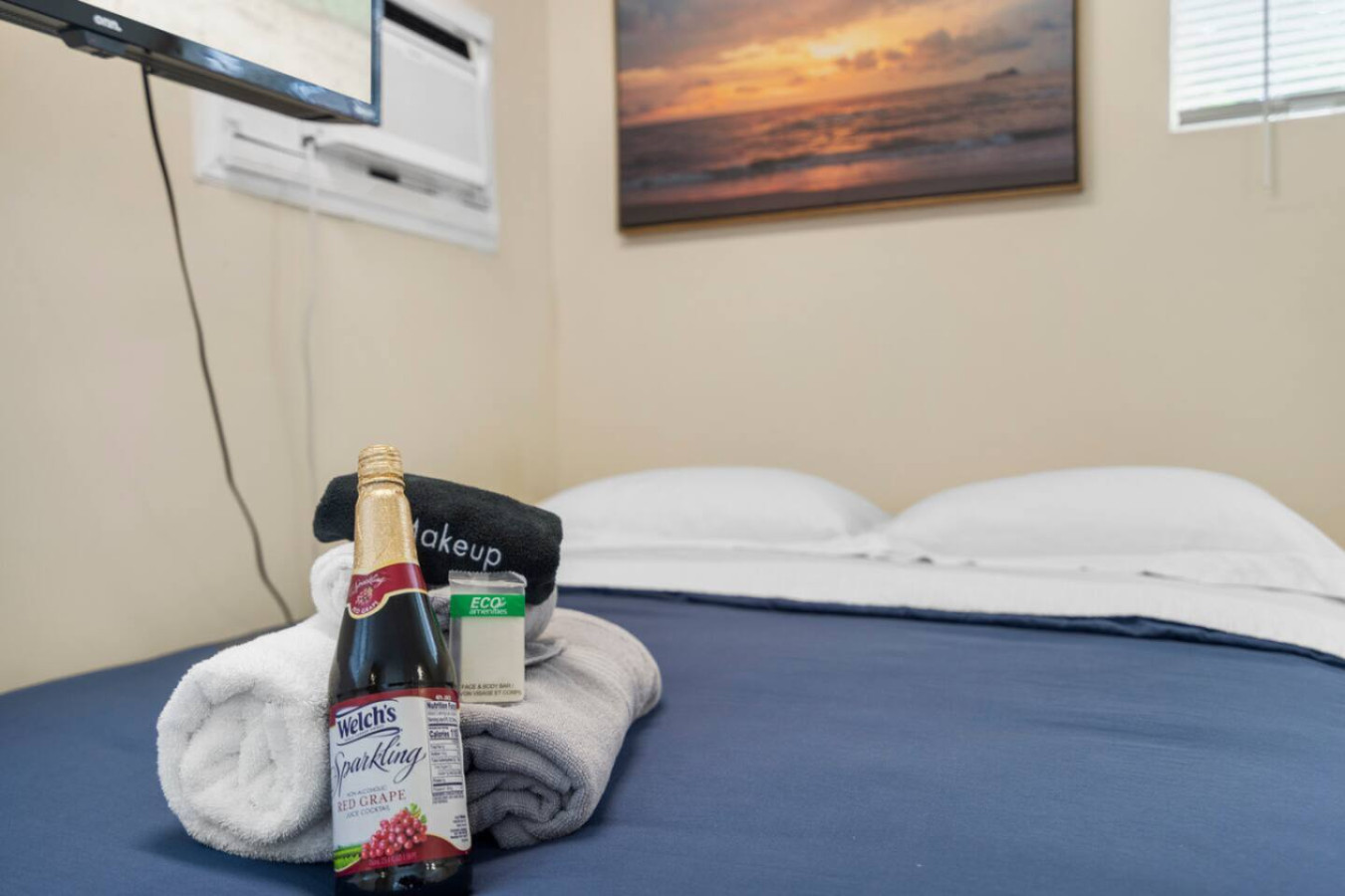 The guest house bedroom, with a wall-mounted TV and a framed sunset print over the bed.