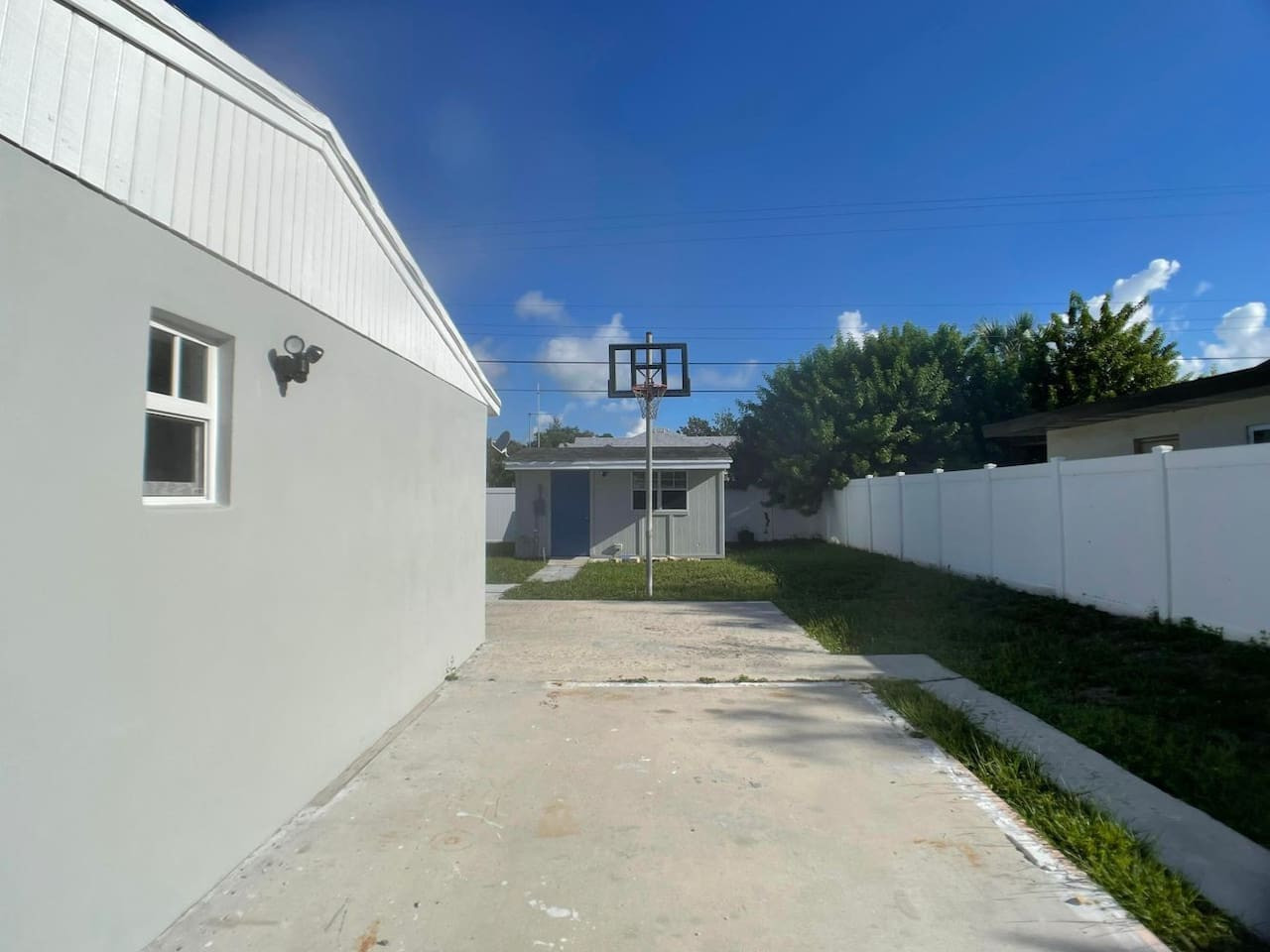 A longer view down the driveway, past the basketball hoop, toward the separate entrance to the backyard guest house.