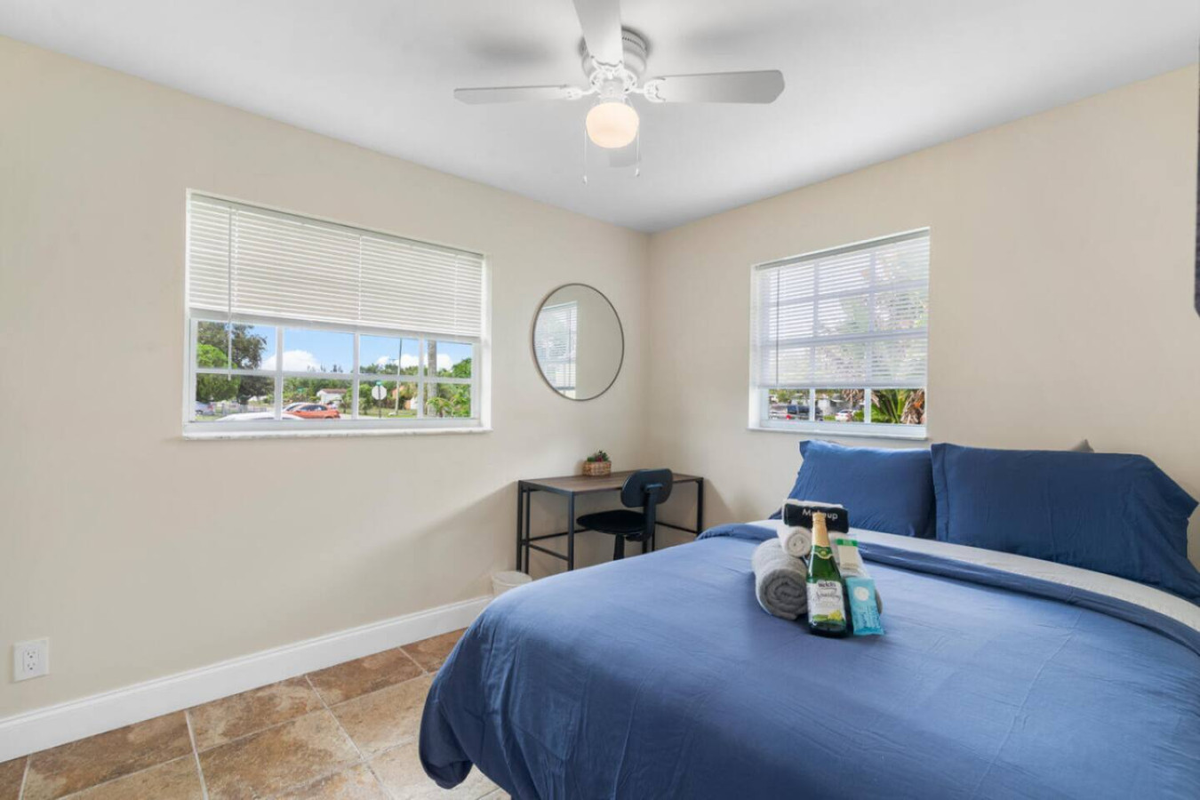 A second bedroom's workspace, same setup: a desk and adjustable shades for privacy.