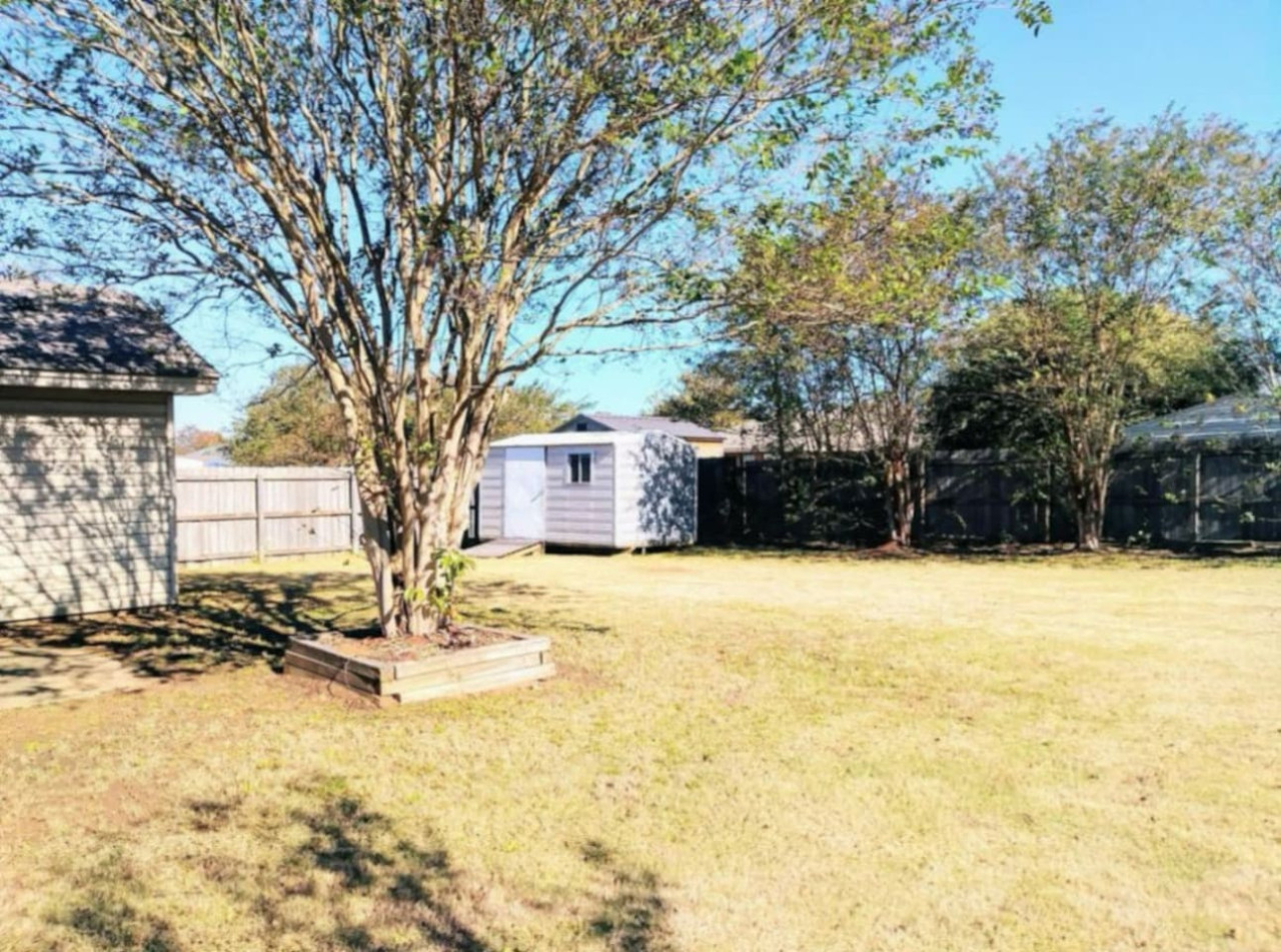 Mature trees shade the large fenced backyard, with room for yard games, family photos or a small group gathered outside.