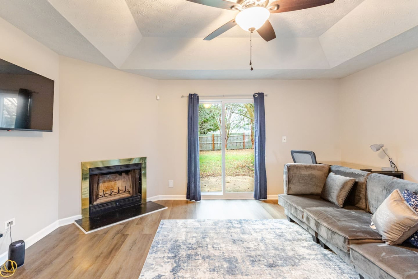 A fireplace and smart TV anchor the living room, and sliding doors open straight onto the backyard.