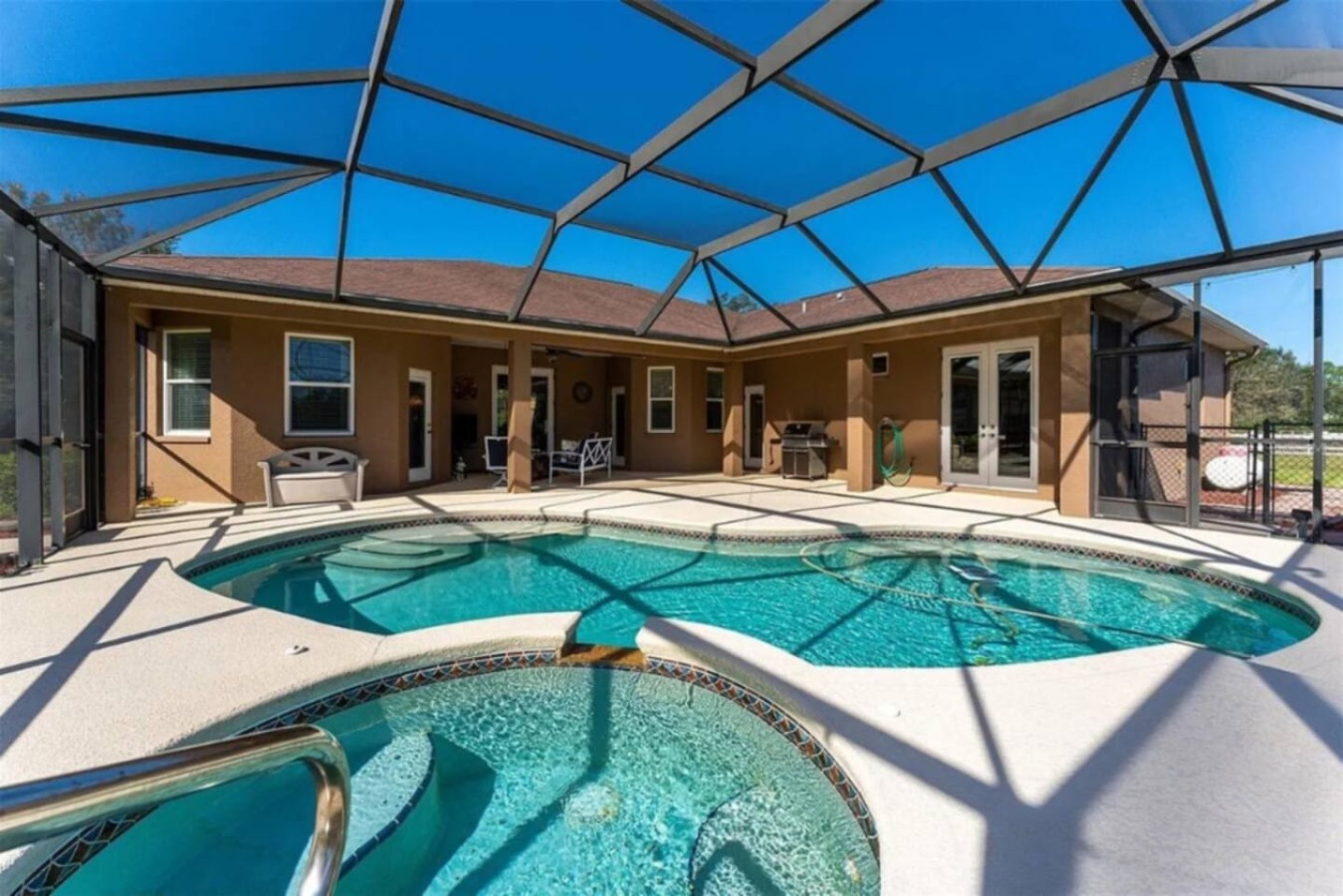 Pool and hot tub share the same screened lanai, swim laps and then soak without leaving the covered space.