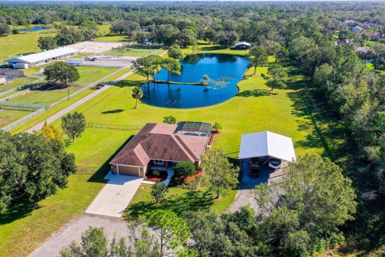 One aerial shot covers three of the property's best assets at once: the lake, the house, and the RV carport tucked to the side.