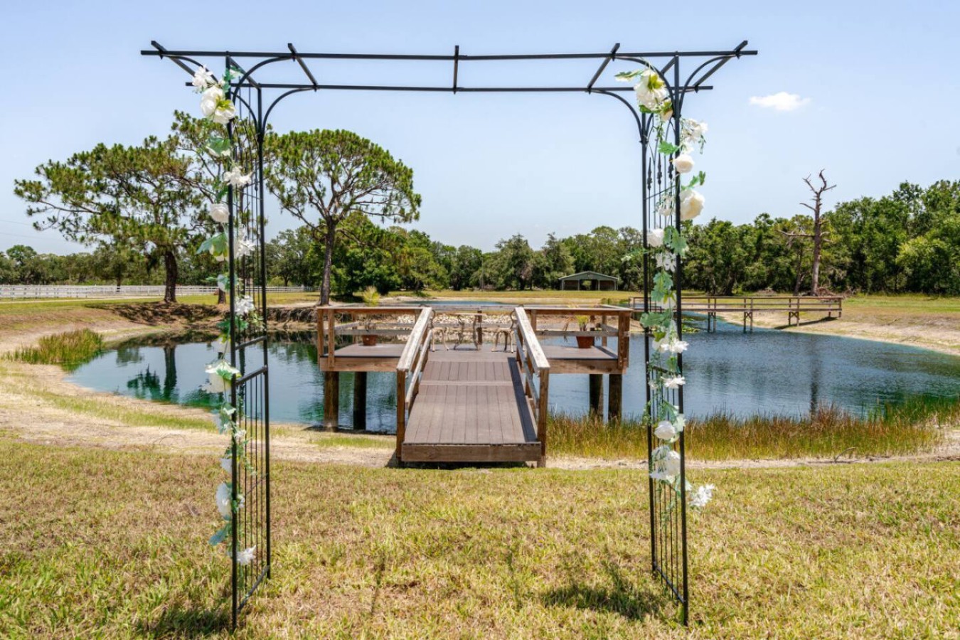 A dock extends out over the pond, with a simple arbor structure already in place, useful for anyone in the group who wants an outdoor gathering spot with water on three sides.