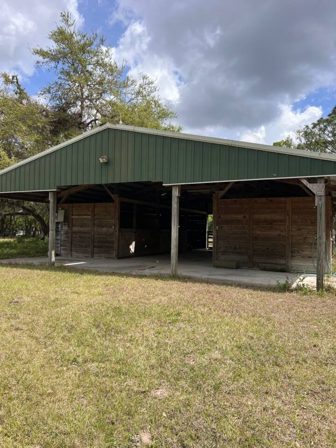 A renovated horse stable stands toward the back of the property, no longer housing horses, now a usable structure for group activities or overflow gathering space.