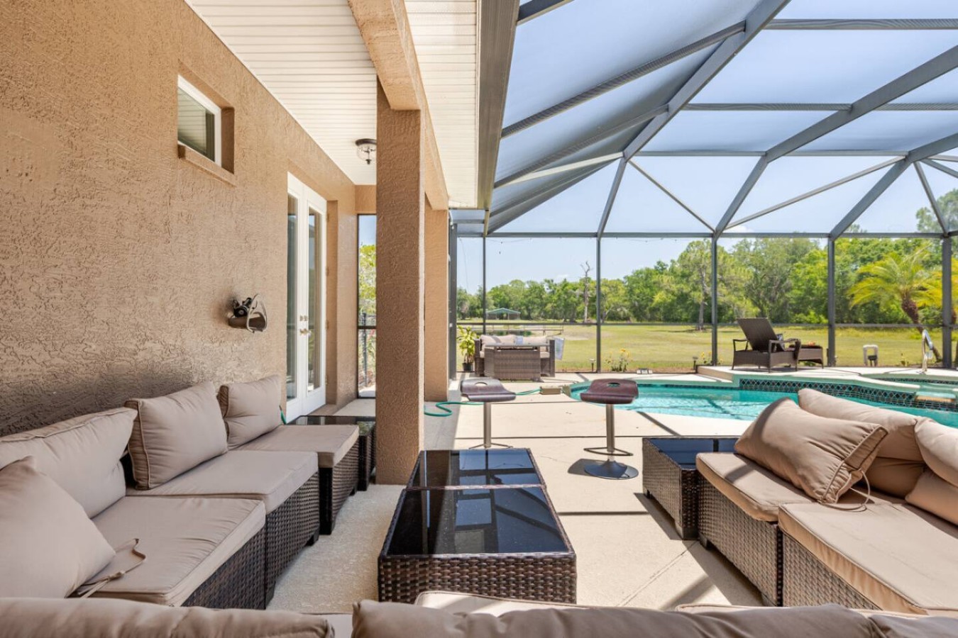 Covered lanai seating just off the pool, shade for the adults while the kids stay in view.