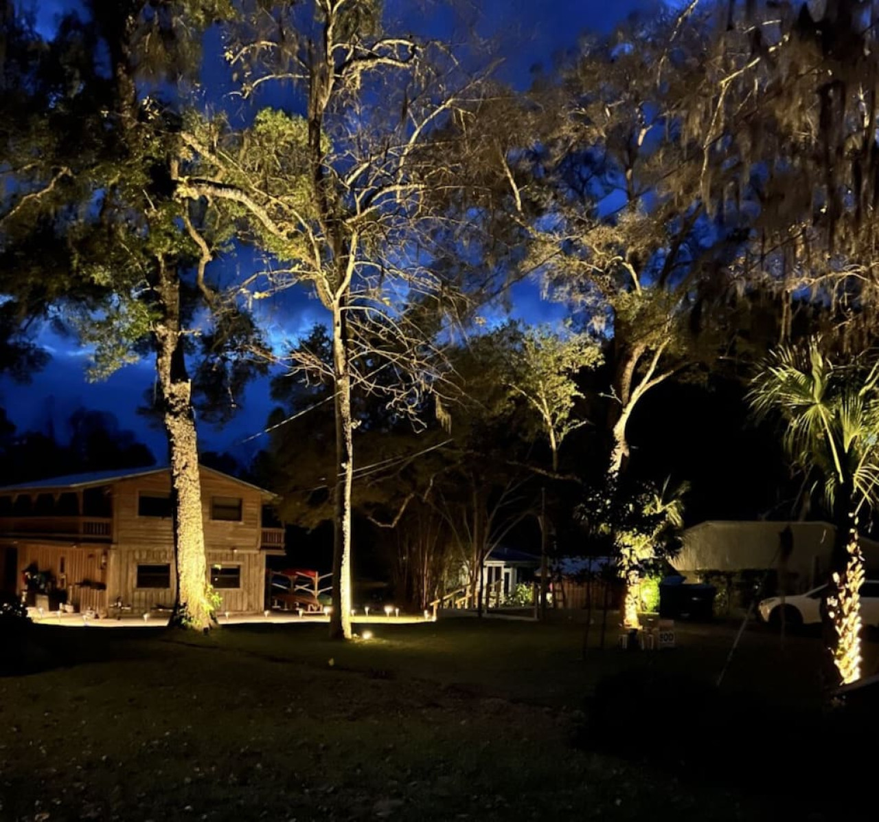 The house at dusk, with the oaks uplit
