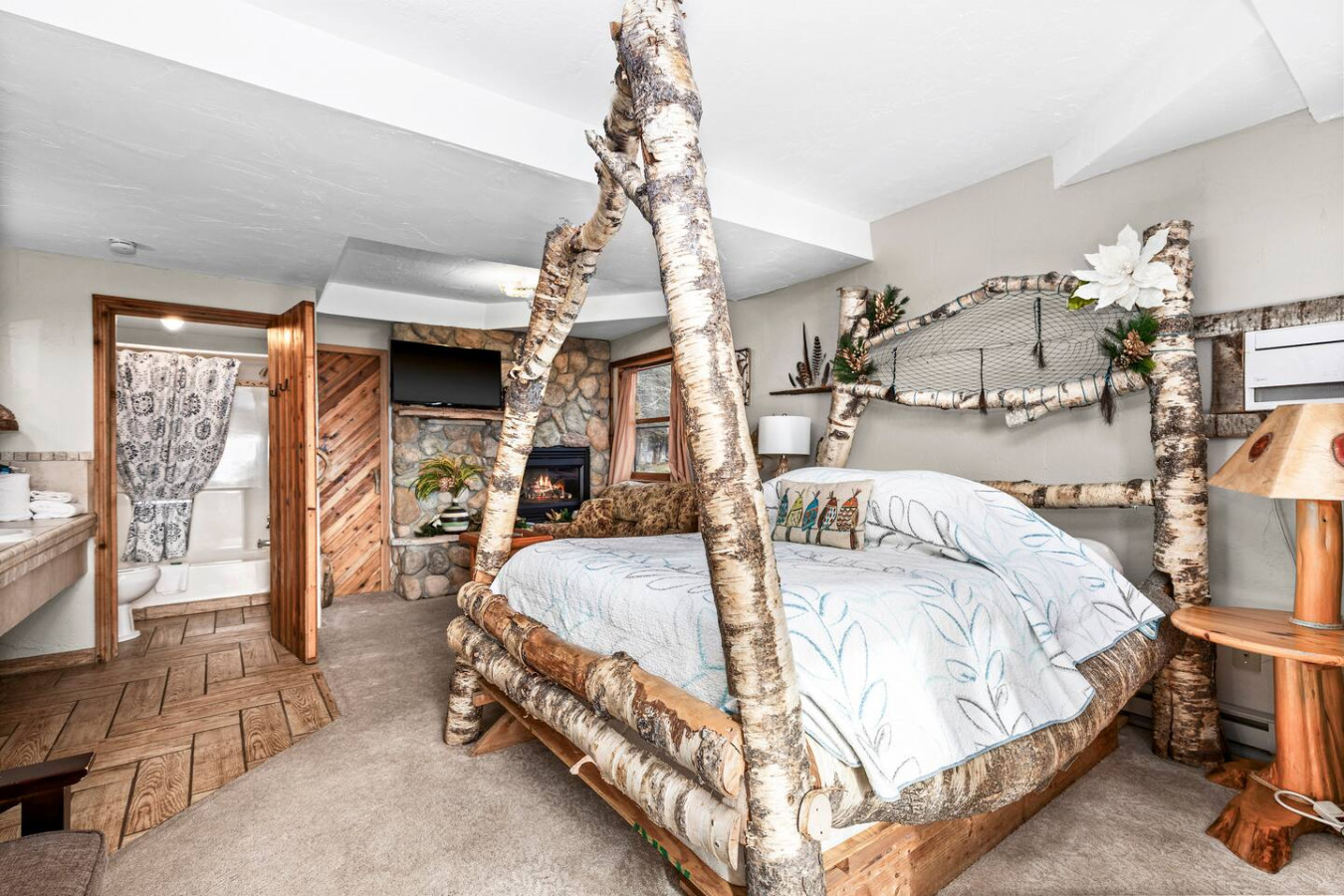 Spacious room with handcrafted birch queen bed and gas fireplace.