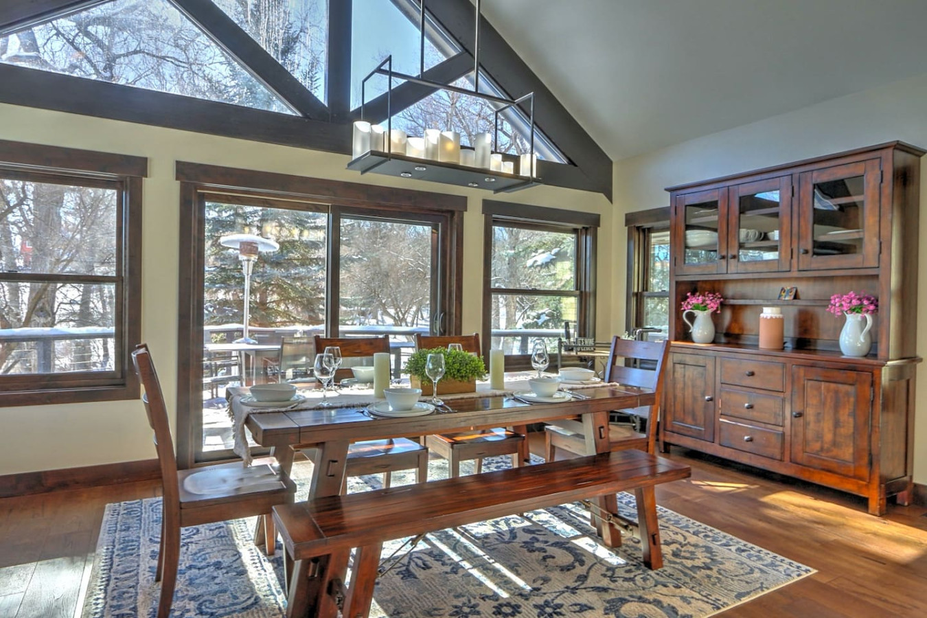 Open living area with vaulted ceilings, expansive windows, and indoor and outdoor dining