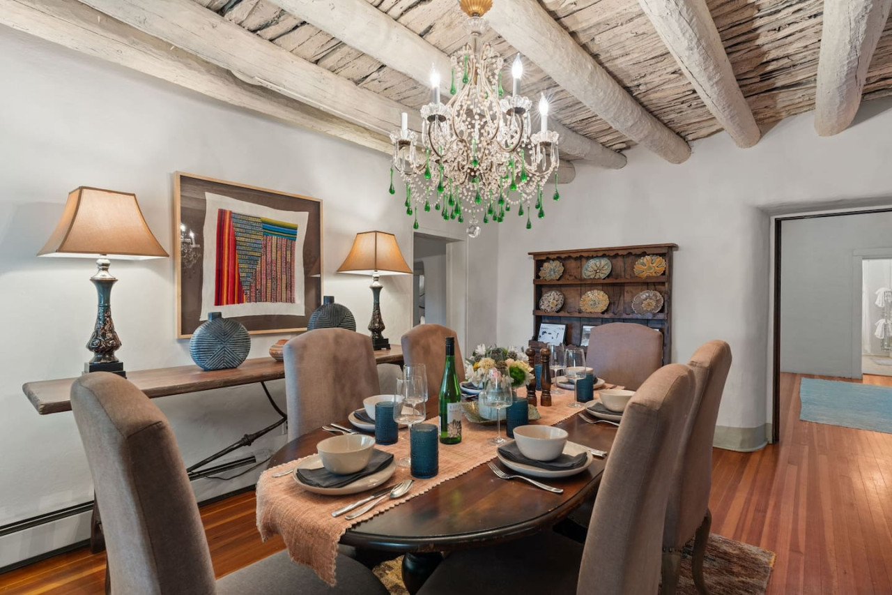 The main house dining table set beneath historic timber vigas
