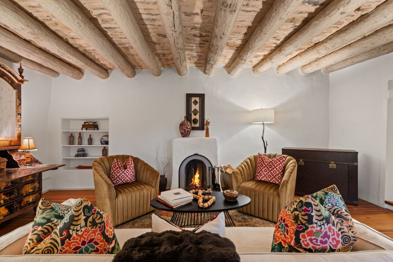 The Boyle House living room with historic vigas, adobe fireplace, and inviting seating