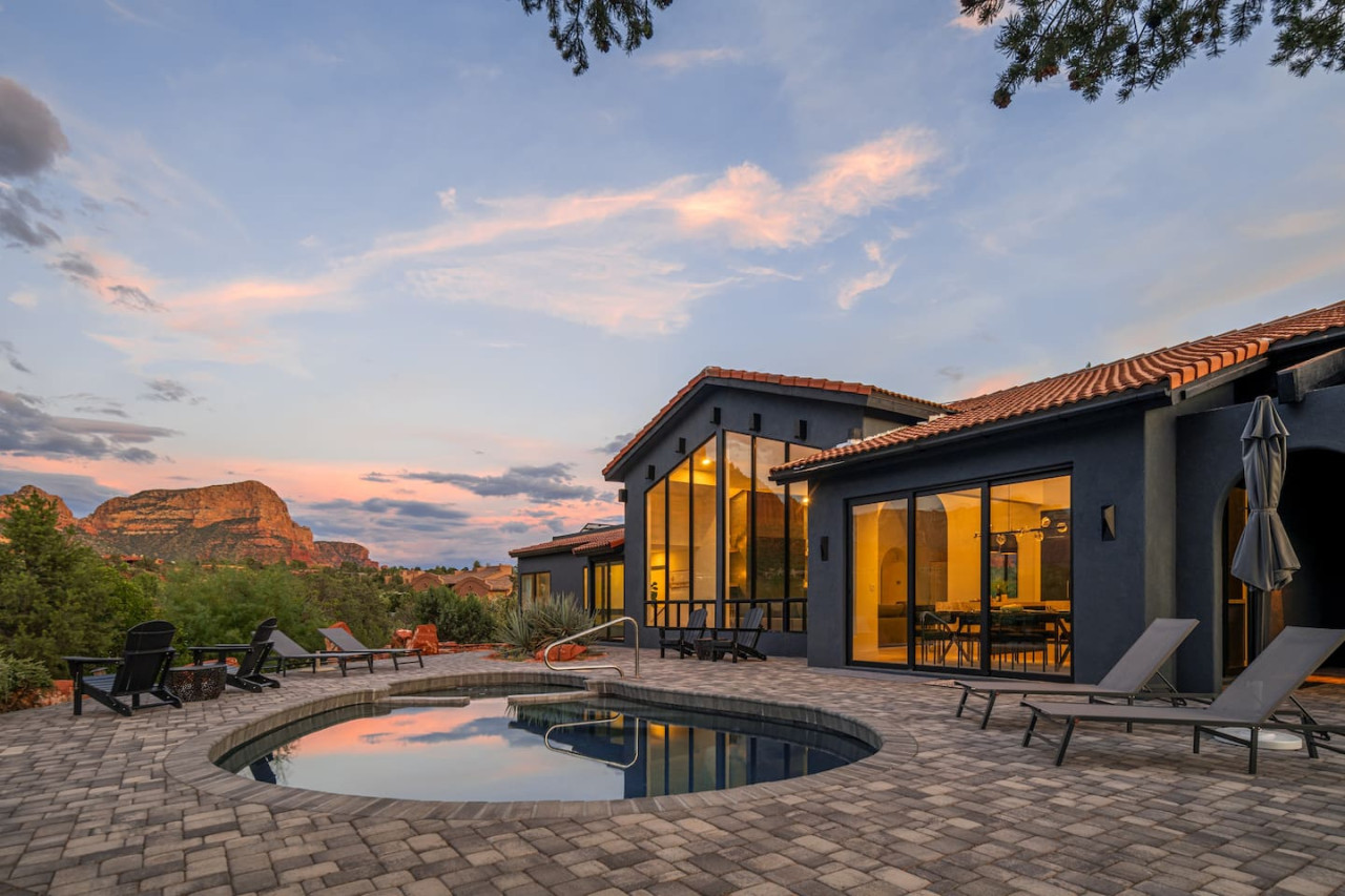 Sleek Sedona Airbnb with circular pool and panoramic desert views beneath a glowing sunset.