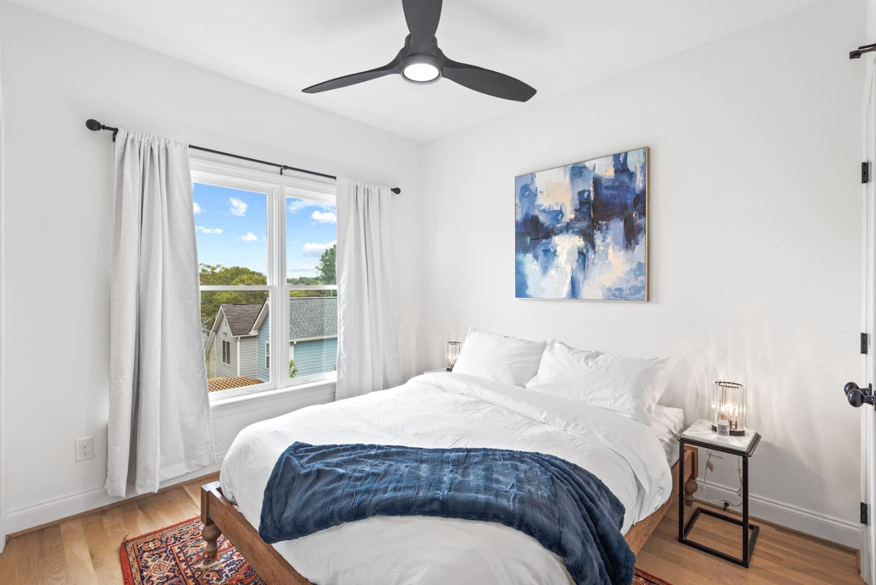 Queen bed in the guest bedroom with a TV.