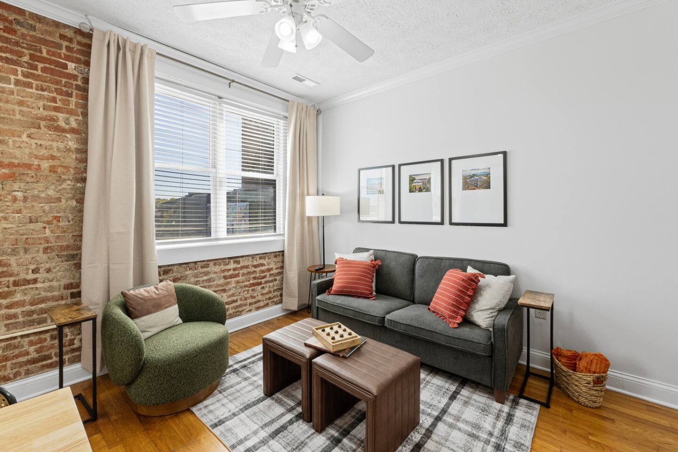 Unwind in this charming corner of the Scots Suite, featuring exposed brick walls, natural light from large windows, and cozy seating. The modern decor and comfortable couch make this space perfect for relaxation or enjoying a quiet evening.