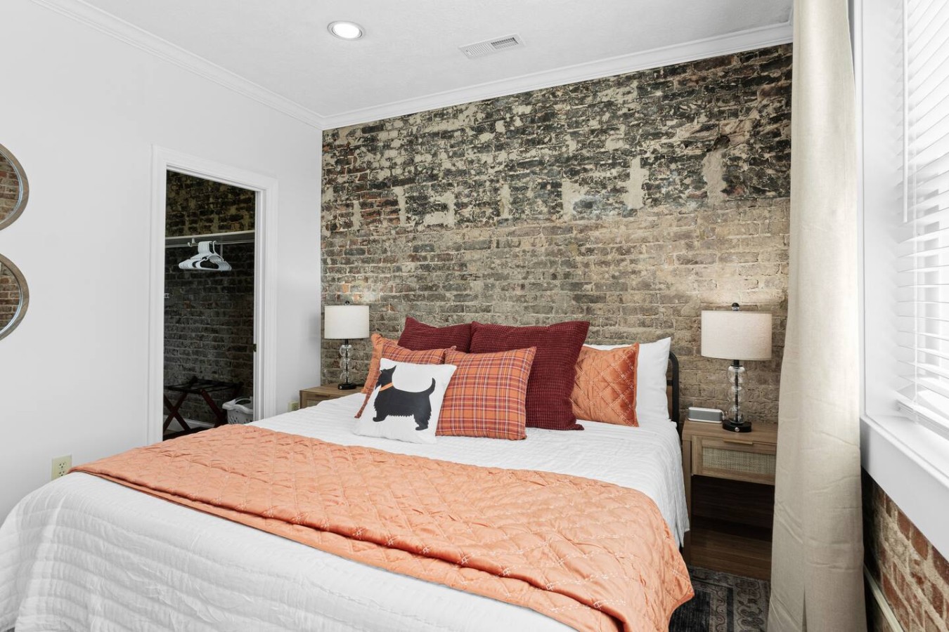 Drift off in this spacious king-size bed, surrounded by the warmth of exposed brick and cozy, colorful bedding. The charming décor, including the Scottie dog pillow, adds a playful, personal touch to this inviting and restful space.