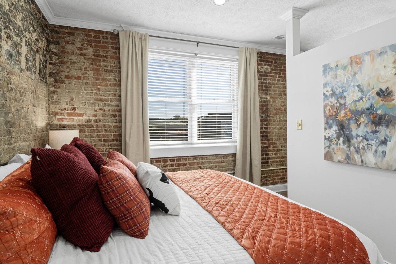 Enjoy natural light from a large window overlooking Broadway Avenue in downtown Maryville, directly above the popular Bella Restaurant. The exposed brick walls and cozy bedding create a warm, inviting space perfect for relaxation.