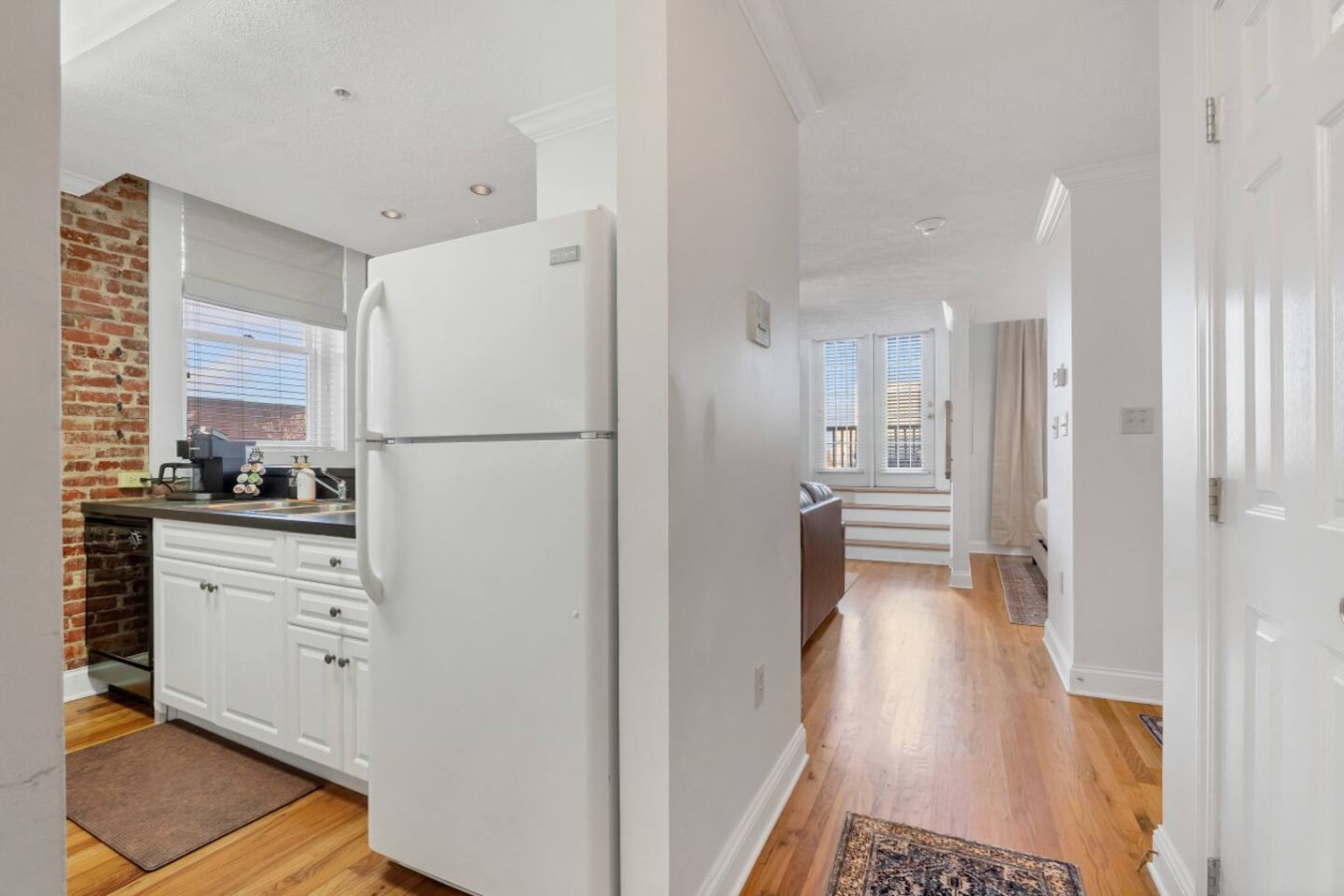 A bright hallway view showcasing the fully equipped kitchen and cozy living area, leading to a private rooftop patio and king-sized bedroom space.