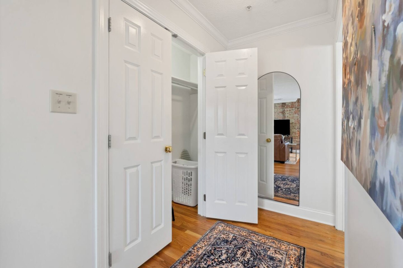 Spacious bedroom with a walk-in closet, full-length mirror, and elegant hardwood floors. Thoughtfully designed for comfort and convenience, offering plenty of storage and a stylish touch to your stay.