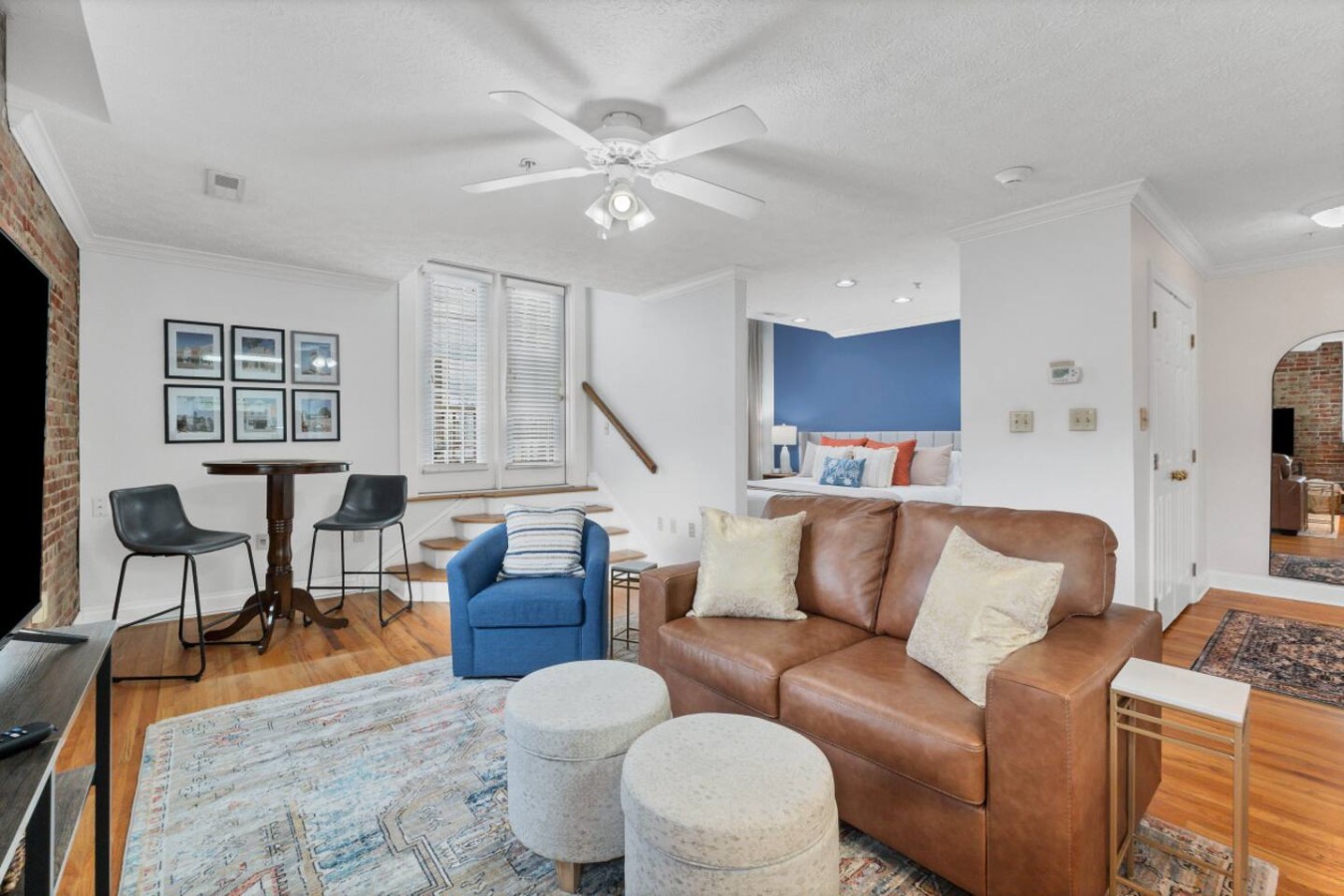 Spacious downtown loft featuring exposed brick walls, a cozy seating area, and a king-sized bed in a stylish open layout. Enjoy natural light from large windows and access to a private rooftop patio for a true downtown Maryville experience.