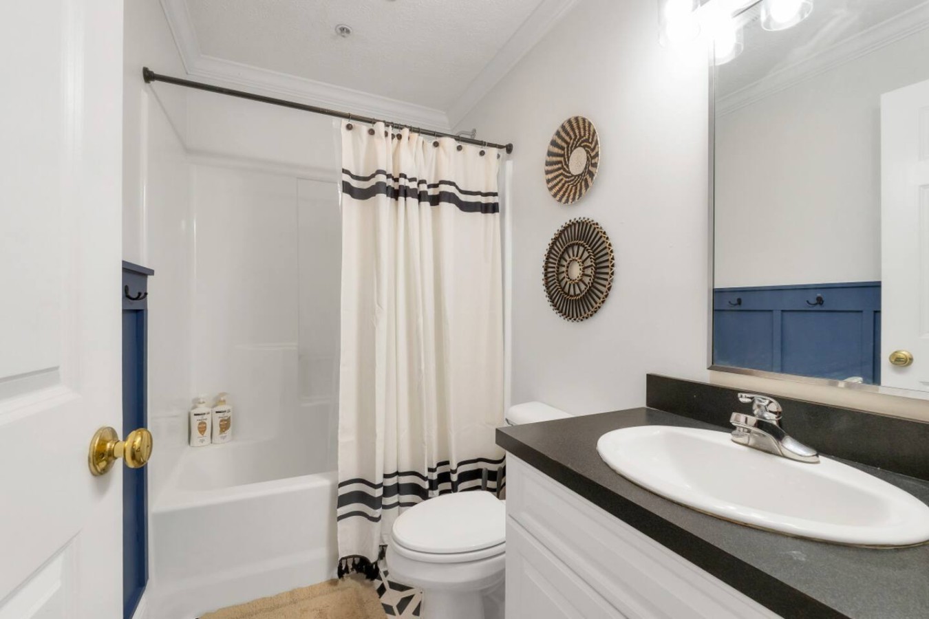Bright and stylish bathroom featuring a modern vanity, clean white finishes, and a shower/tub combo with complimentary toiletries. Thoughtful decor and soft lighting create a relaxing space for your stay.