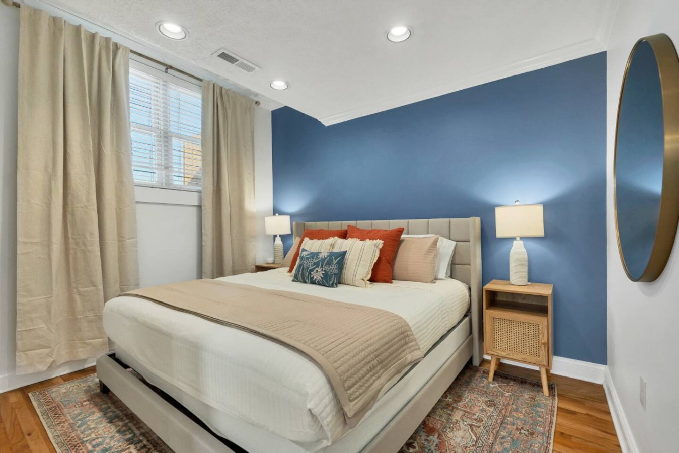 Relax in a serene bedroom featuring a plush king bed, elegant decor, and warm lighting. The deep blue accent wall and soft neutral tones create a cozy retreat perfect for unwinding after a day of exploring.