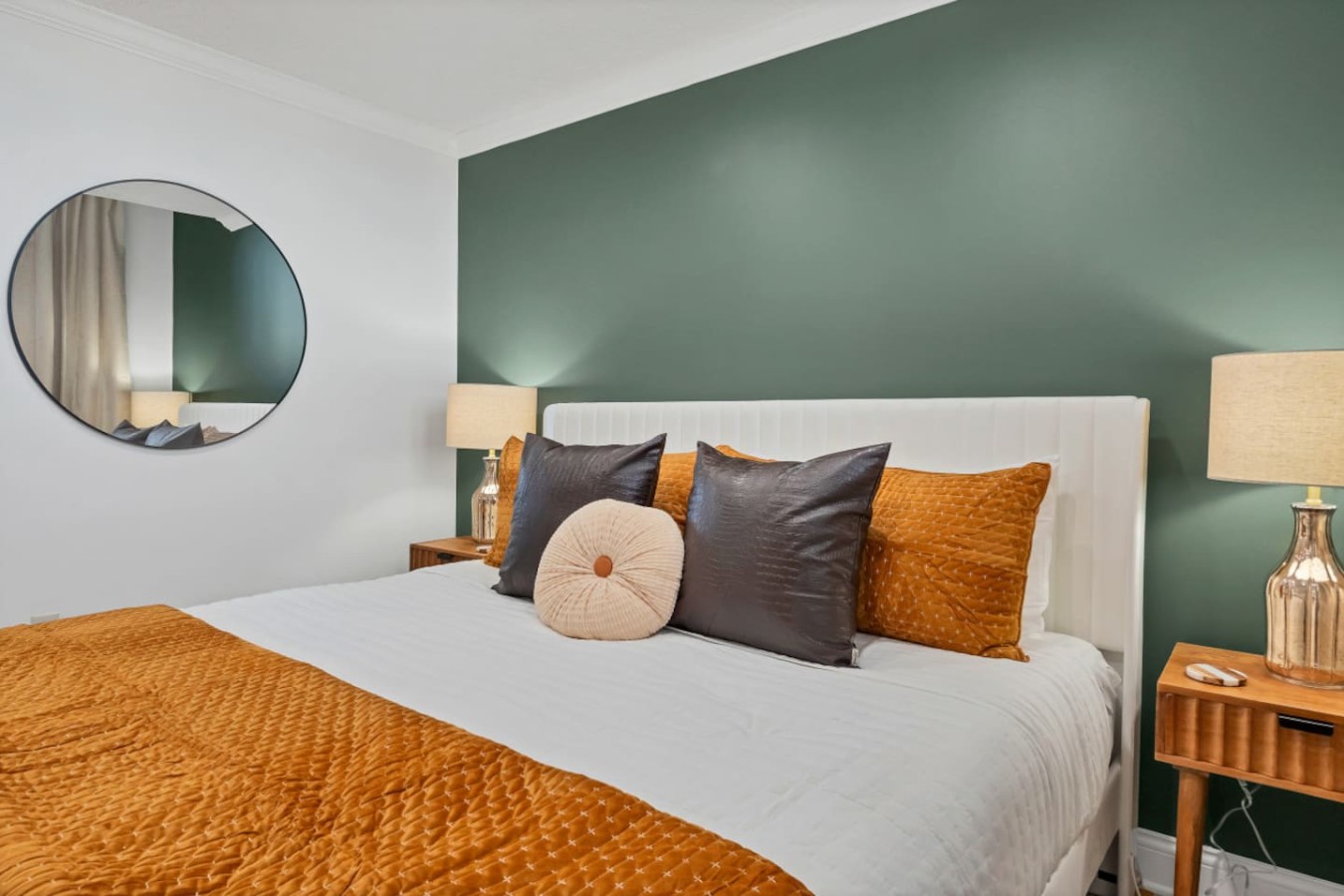 Unwind in the luxurious king bed with plush pillows and warm-toned bedding. A chic green accent wall and soft lighting create a cozy, stylish retreat in the heart of downtown Maryville.