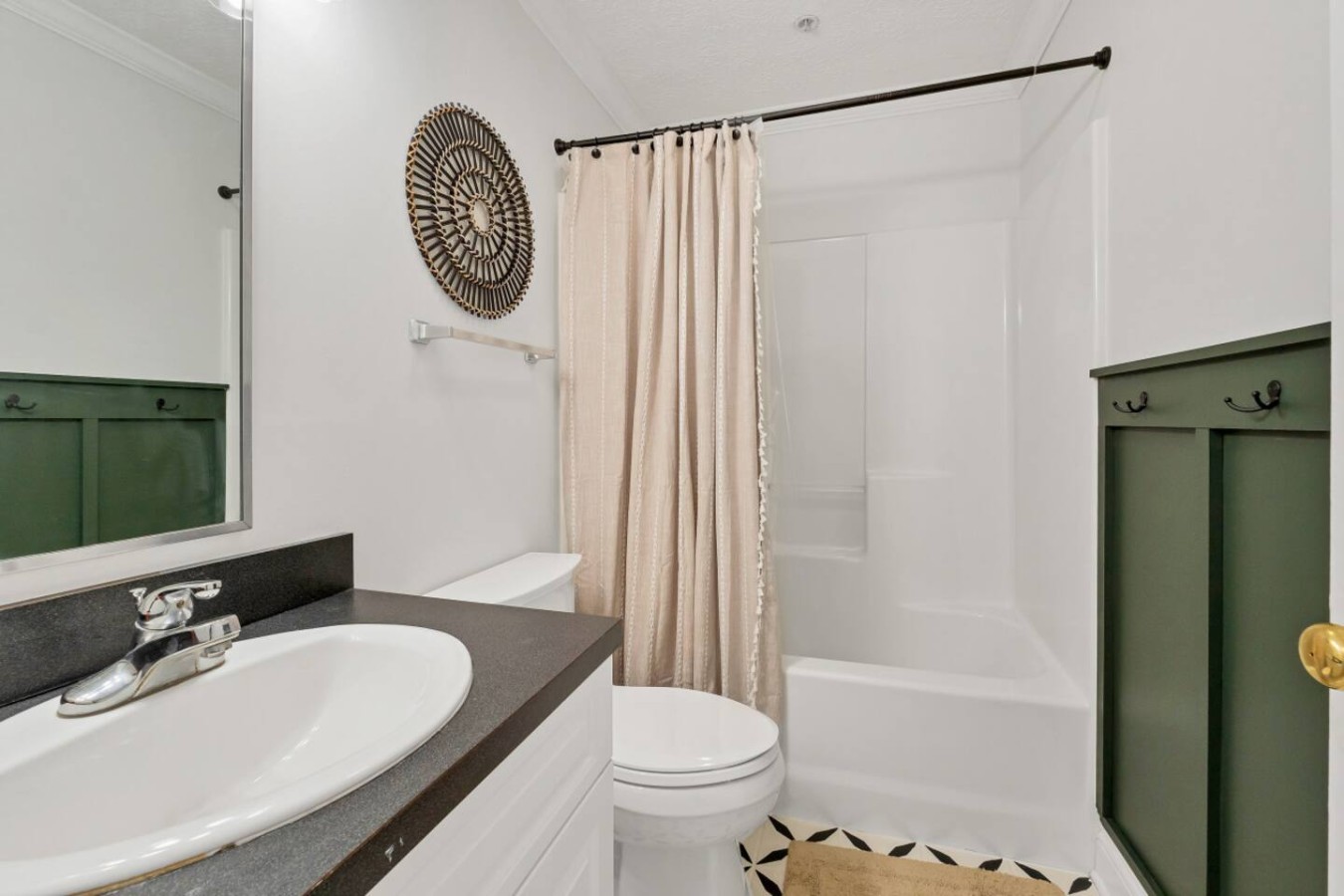Stylish full bathroom with modern touches, a tub-shower combo, and fresh towels. Green cabinetry adds charm, creating a relaxing retreat after exploring downtown Maryville.