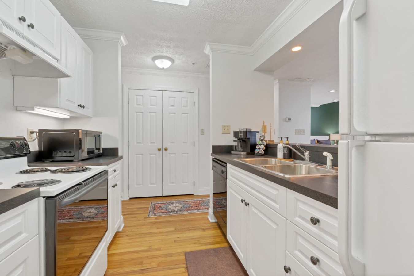Spacious galley kitchen with modern appliances, ample counter space, and a fully stocked coffee station. Features a double sink and plenty of storage, making meal prep a breeze. Conveniently located near the open living area for easy entertaining.