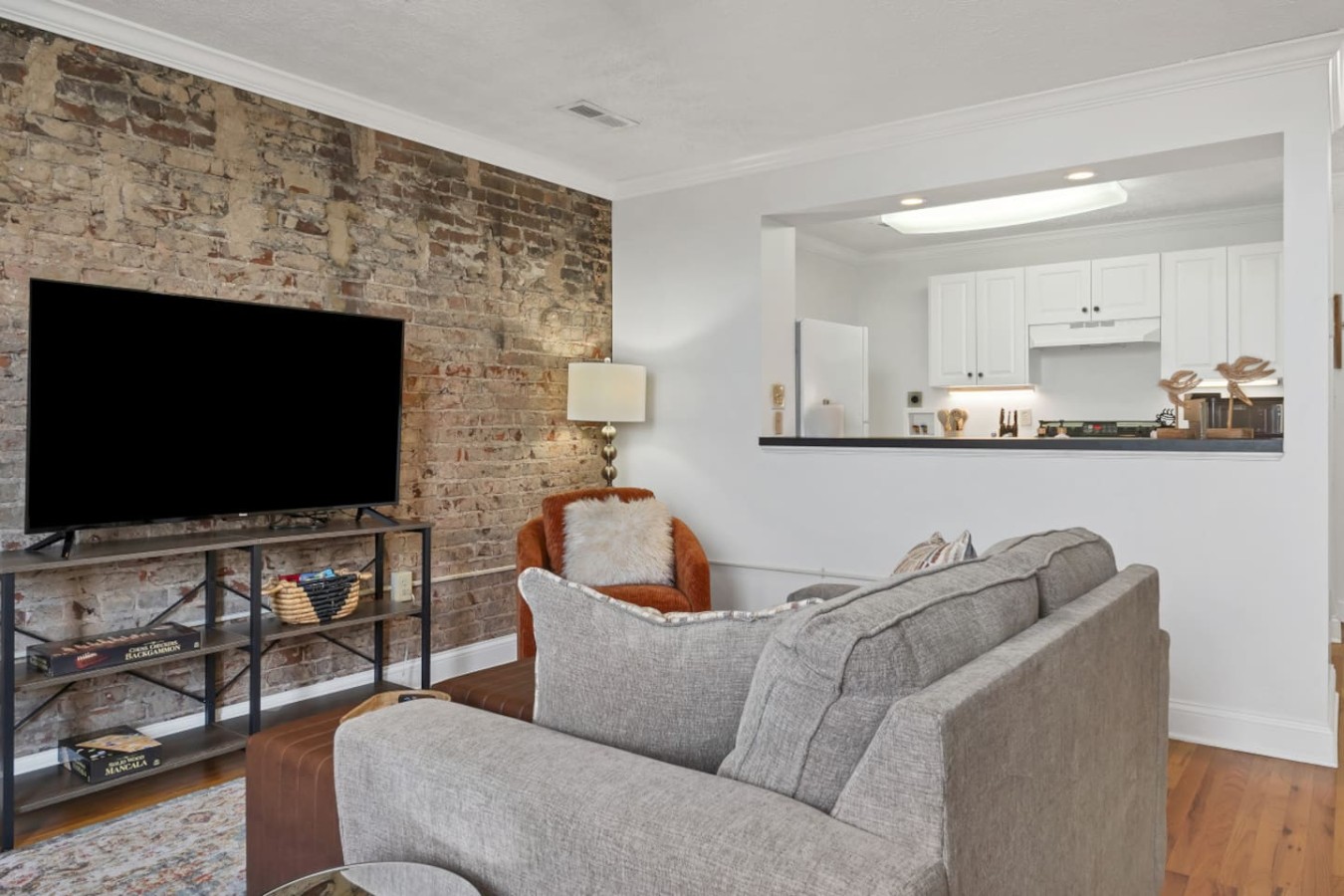 Inviting living space with exposed brick, plush seating, and a large TV. Open-concept layout flows into a fully equipped kitchen. Perfect for relaxing after exploring downtown Maryville’s dining and entertainment scene, just steps from your door.