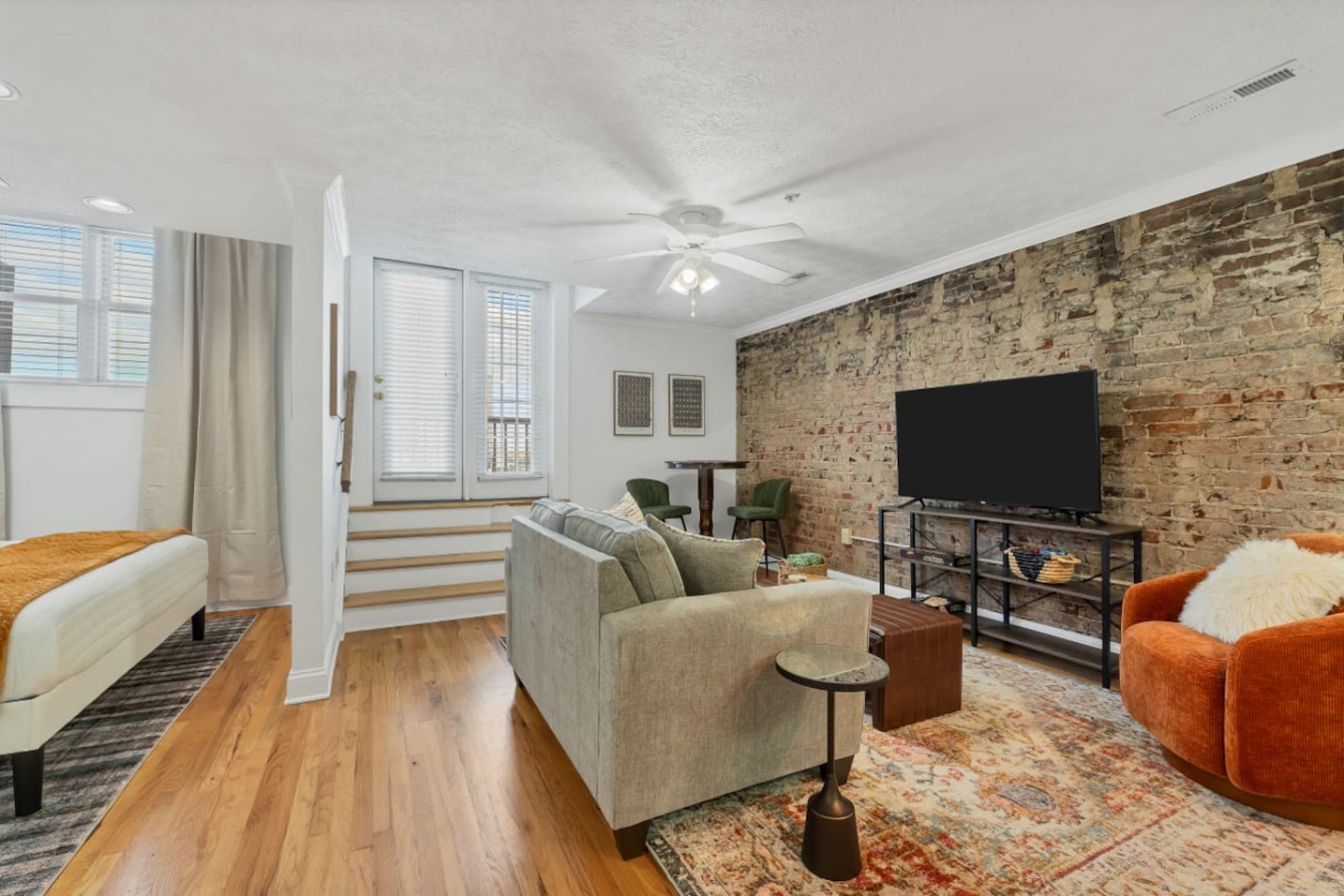 Chic living area with exposed brick, plush seating, and large TV. An inviting space perfect for relaxing after exploring downtown Maryville’s shops, restaurants, and historic charm.