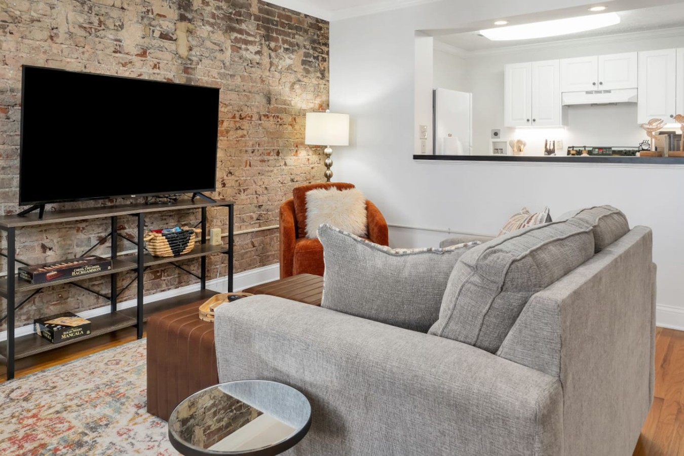 Cozy living space with exposed brick, plush seating, and a large TV. Enjoy a movie night or unwind after a day in downtown Maryville. The open layout seamlessly connects to the fully equipped kitchen for effortless entertaining.