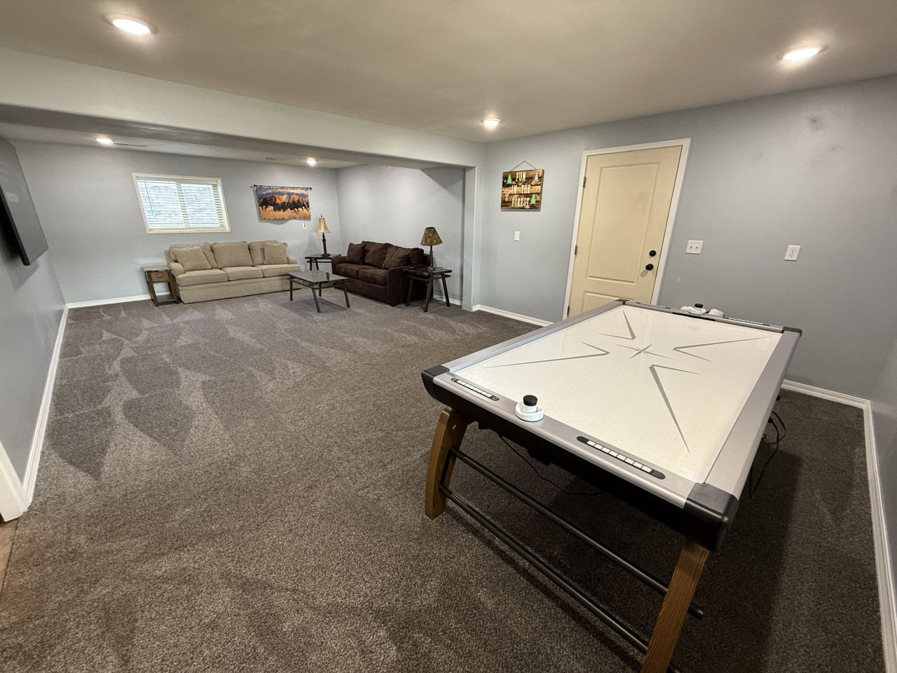 Air hockey table and large TV in the basement living room