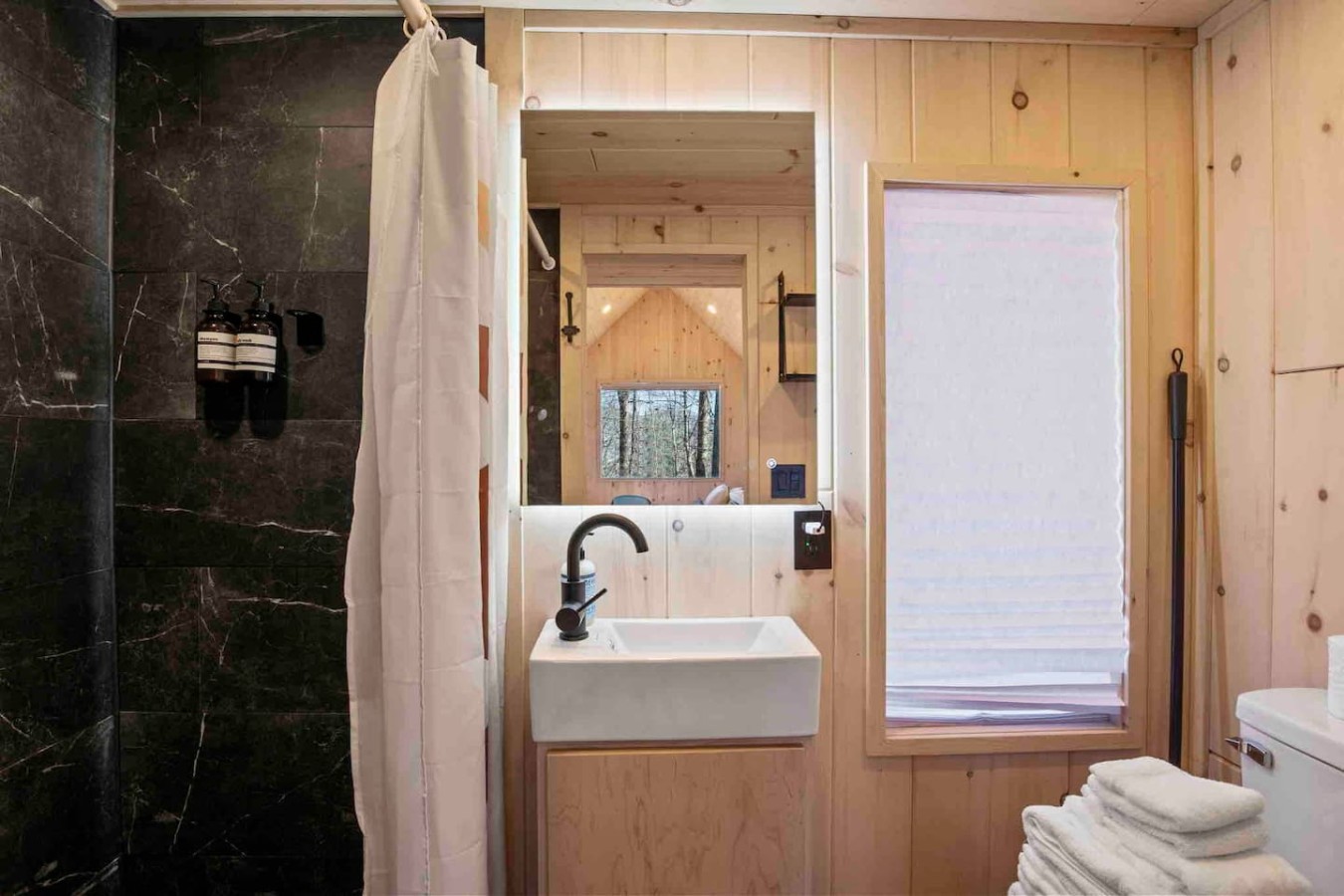 Enjoy a refreshing shower in this stylish bathroom, complete with a sleek sink and a chic mirror