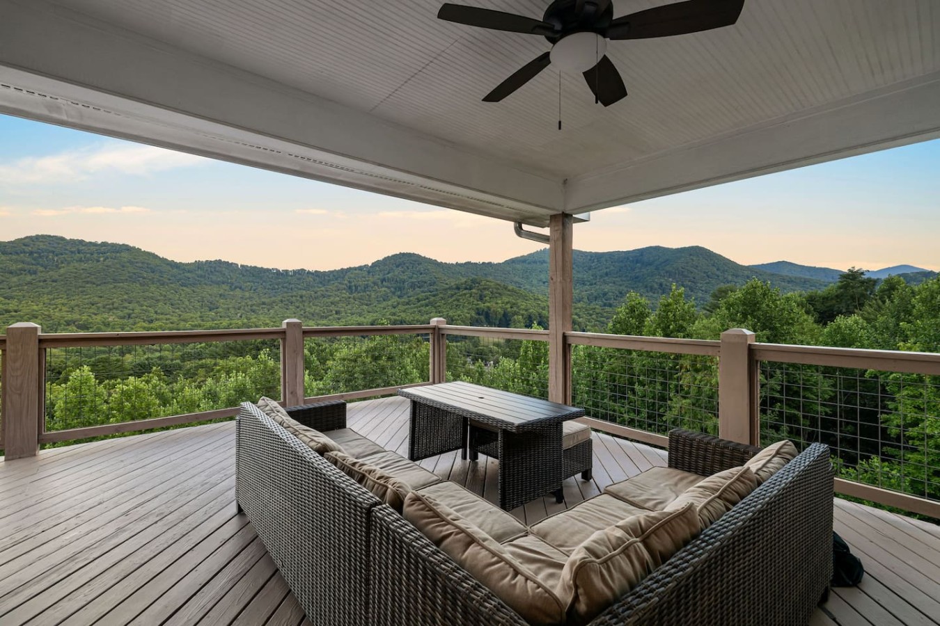 Covered deck with wicker sectional seating and mountain views at a Leisr Stays managed property near Candler, North Carolina