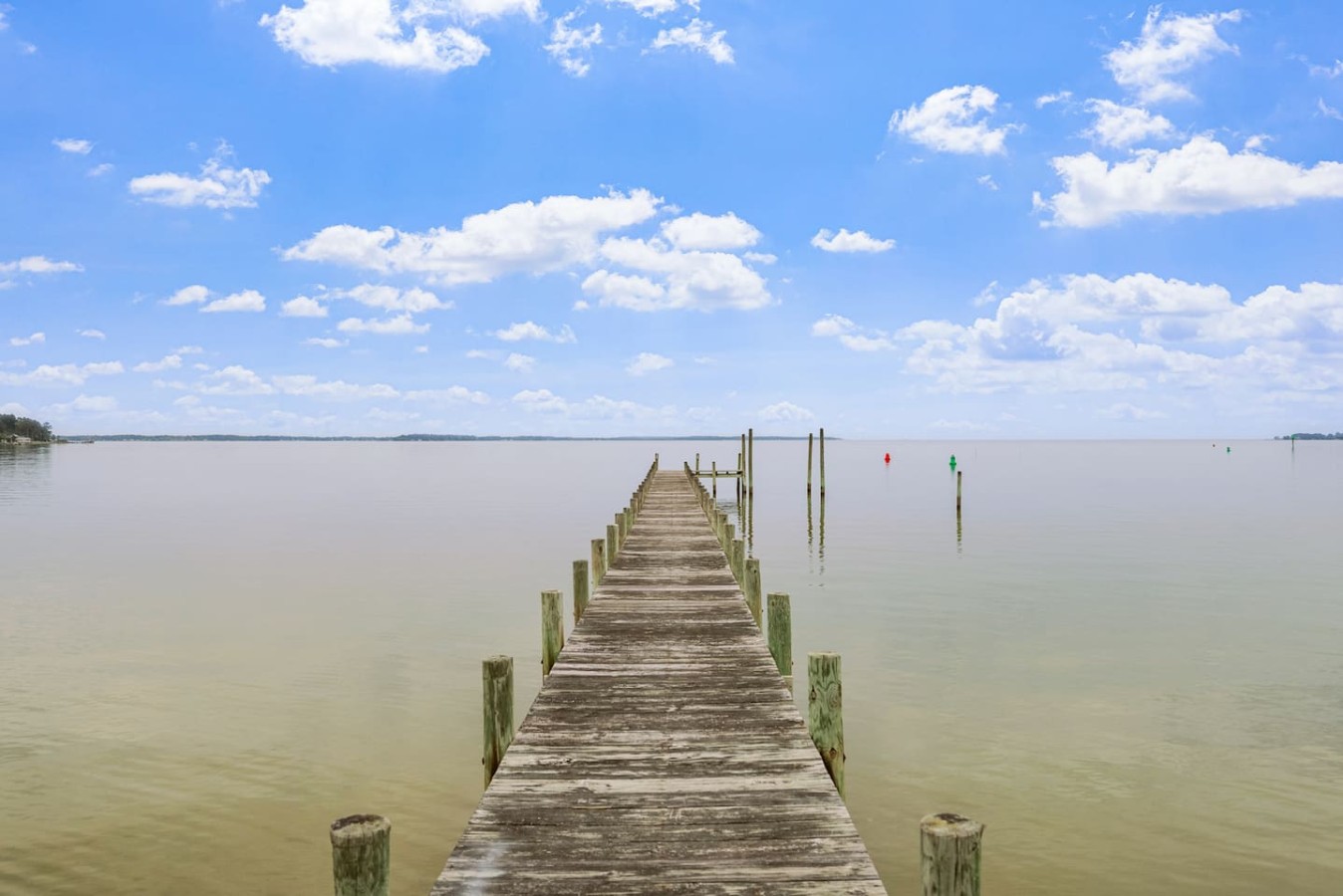 Breathe in the beauty of nature as you stroll along this stunning wooden pier, surrounded by the tranquility of the water and the majestic clouds above!