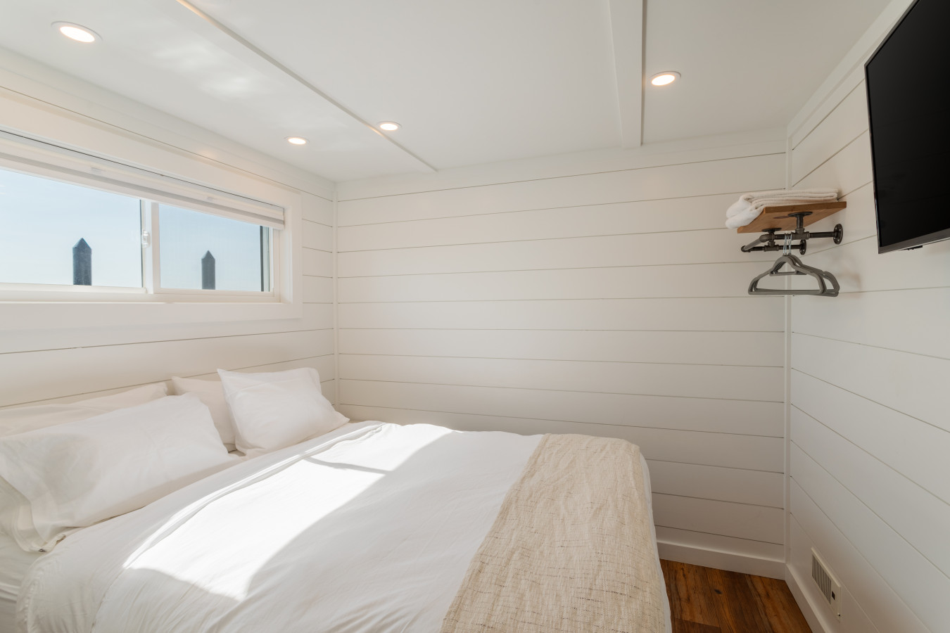 The second bedroom offers a queen bed, smart TV, and sun-filled shiplap walls — simple, clean, and right on the water.