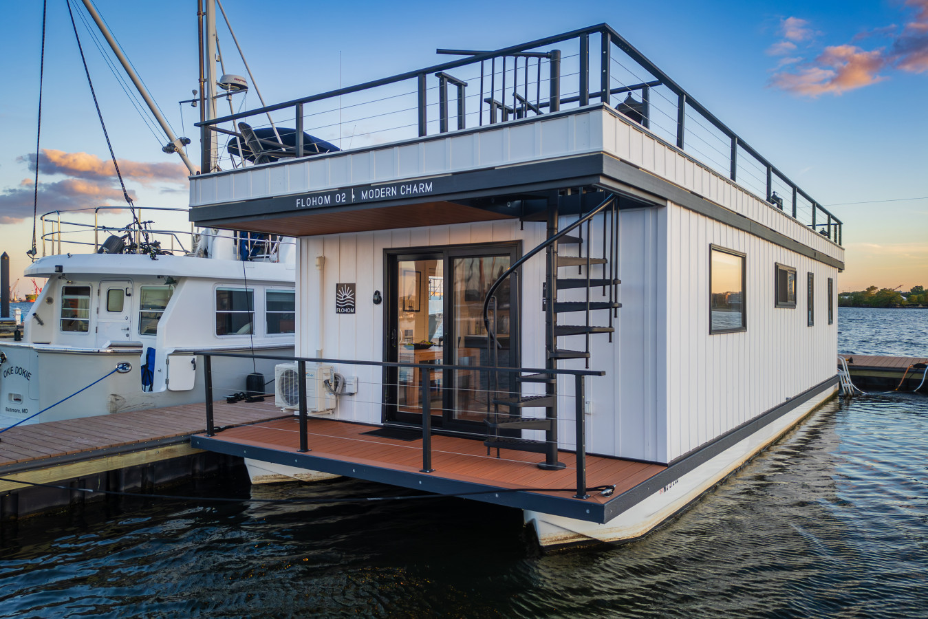 Step aboard this stunning modern houseboat featuring a private rooftop deck, spiral staircase, and waterfront views at golden hour.