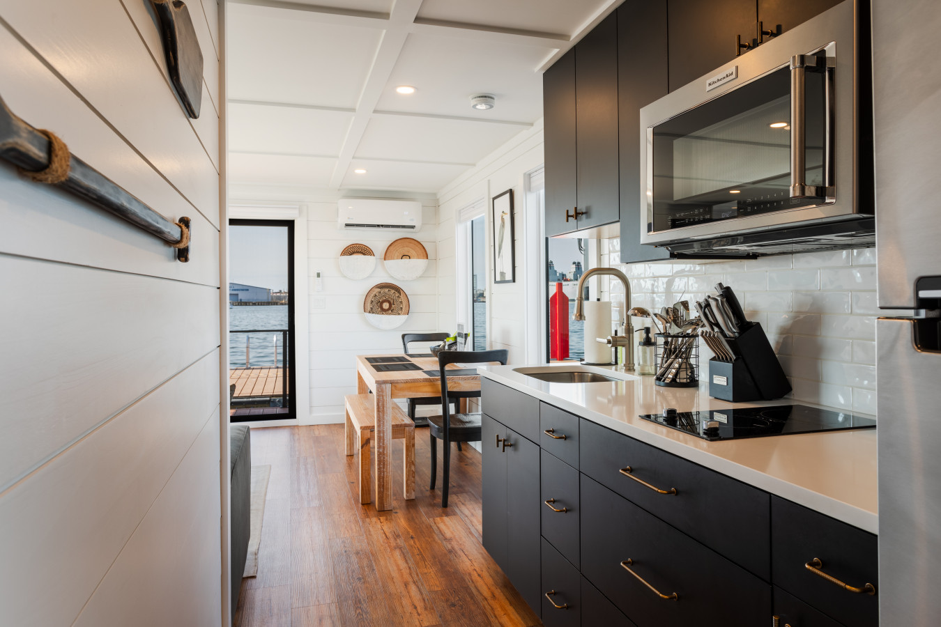 The galley kitchen has everything — microwave, coffee maker, full fridge, and opens straight to the waterfront dining nook.