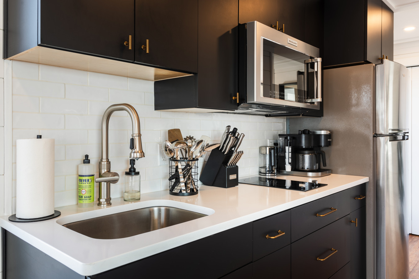 Cook with a view — sleek black cabinets, gold hardware, quartz counters, and everything you need to make meals onboard.