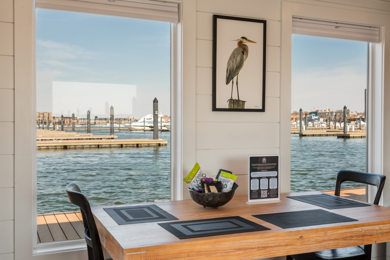 Every meal feels special at this waterfront dining table — marina views on both sides and charming heron art on the wall.