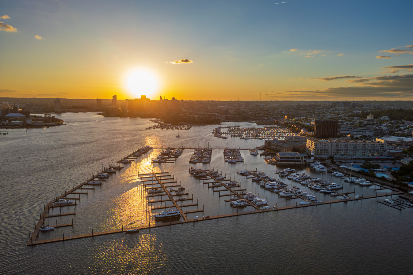 Golden hour magic — a sweeping aerial view of our marina, the harbor, and Baltimore's skyline bathed in sunset light.  ROOFTOP DECK rooftop-dining-sunset-harbor-view.jpg VRBO: Rooftop dining table set against a dramatic golden sunset over Baltimore harbor