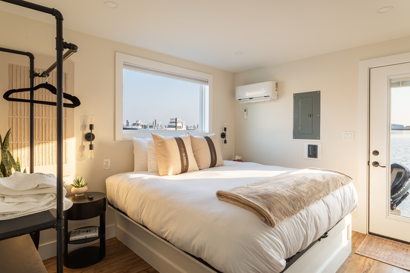 Wake up to harbor views in this sunlit king bedroom with plush bedding and modern industrial accents.