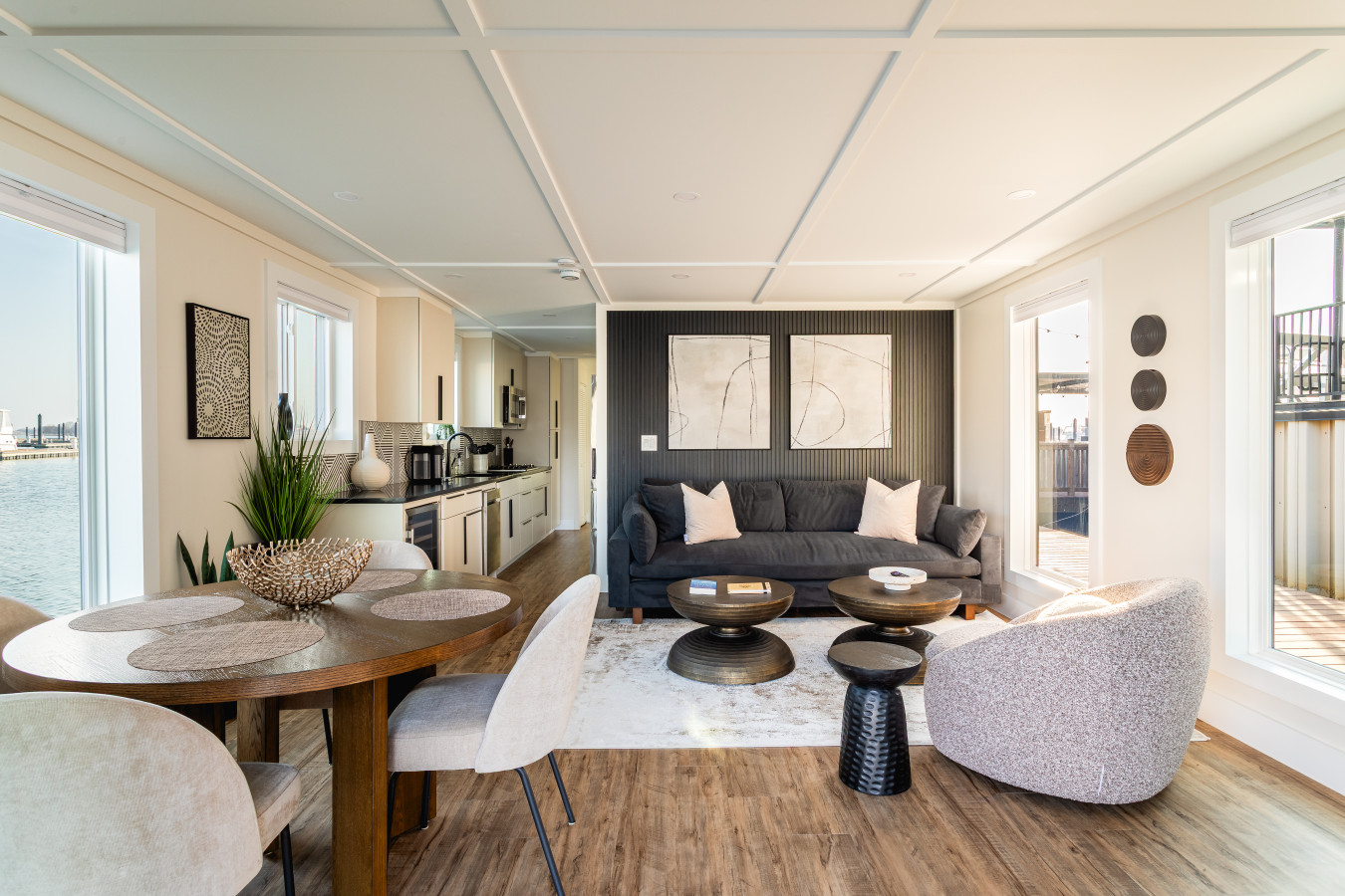 Bright open-concept living and dining space with modern decor and water views from every window.