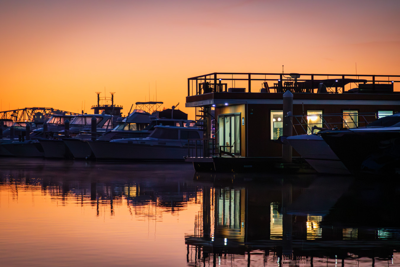 Palmera at sunrise on the Intracoastal Waterway, the interior glowing warmly through the windows as the first light of the morning spreads across the water and the marina.