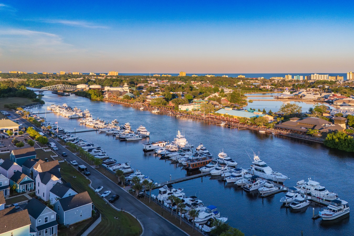An aerial view of Barefoot Marina at golden hour, with the Barefoot Landing entertainment district directly across the Intracoastal and the Atlantic coastline …An aerial view of Barefoot Marina at golden hour, with the Barefoot Landing entertainment distr
