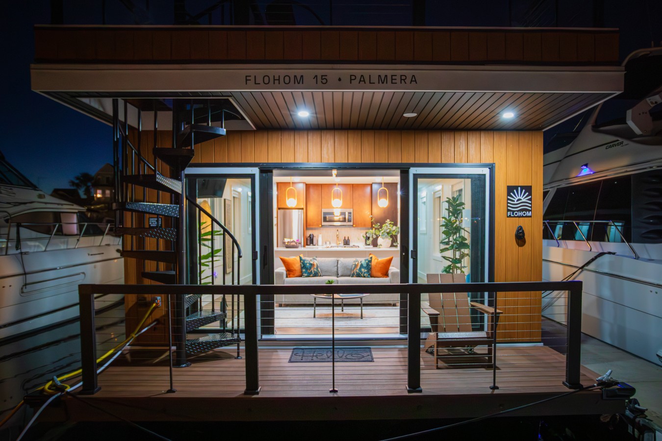 Front-facing twilight view of Palmera with the sliding glass doors open, the warm interior on full display, the spiral staircase leading to the rooftop