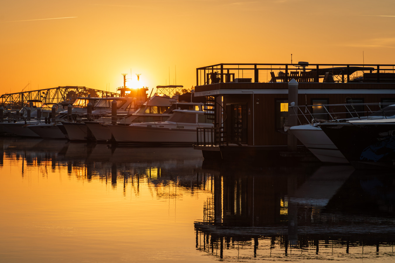 Palmera and the Barefoot Landing Marina at sunrise, the Intracoastal Waterway turned to gold as the sun rises behind the bridge and the rooftop silhouette catches the first light.