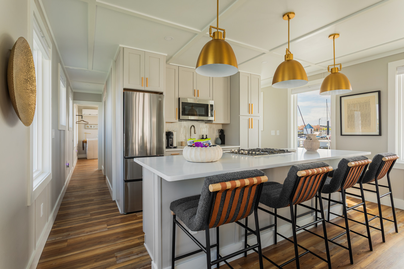 A fully equipped kitchen with a quartz island, gas cooktop, stainless appliances, and four bar stools — ready for everything from morning coffee to a full dinner spread.