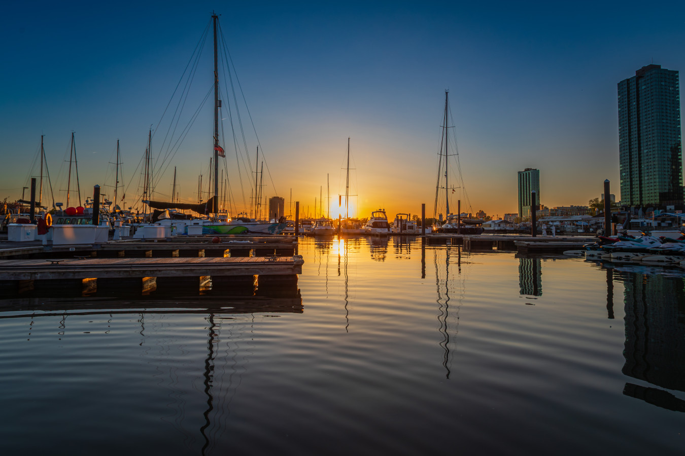 Sunrise at Liberty Landing Marina. Sailboat masts reflected in still water, the day beginning right outside your door