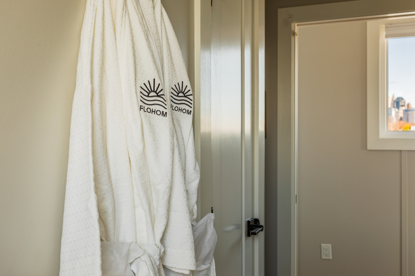 FLOHOM robes are waiting for you, with the Manhattan skyline peeking through the window just behind them.